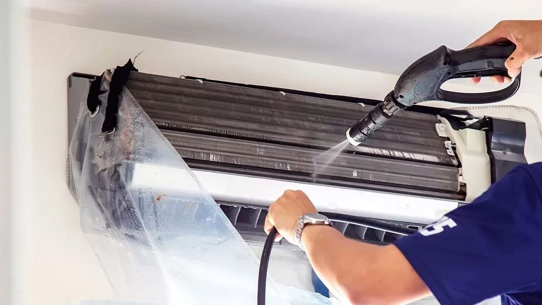 Ảnh minh hoạ: kỹ thuật viên xịt rửa dàn lạnh máy lạnh treo tường, có bạt nylon hứng nước